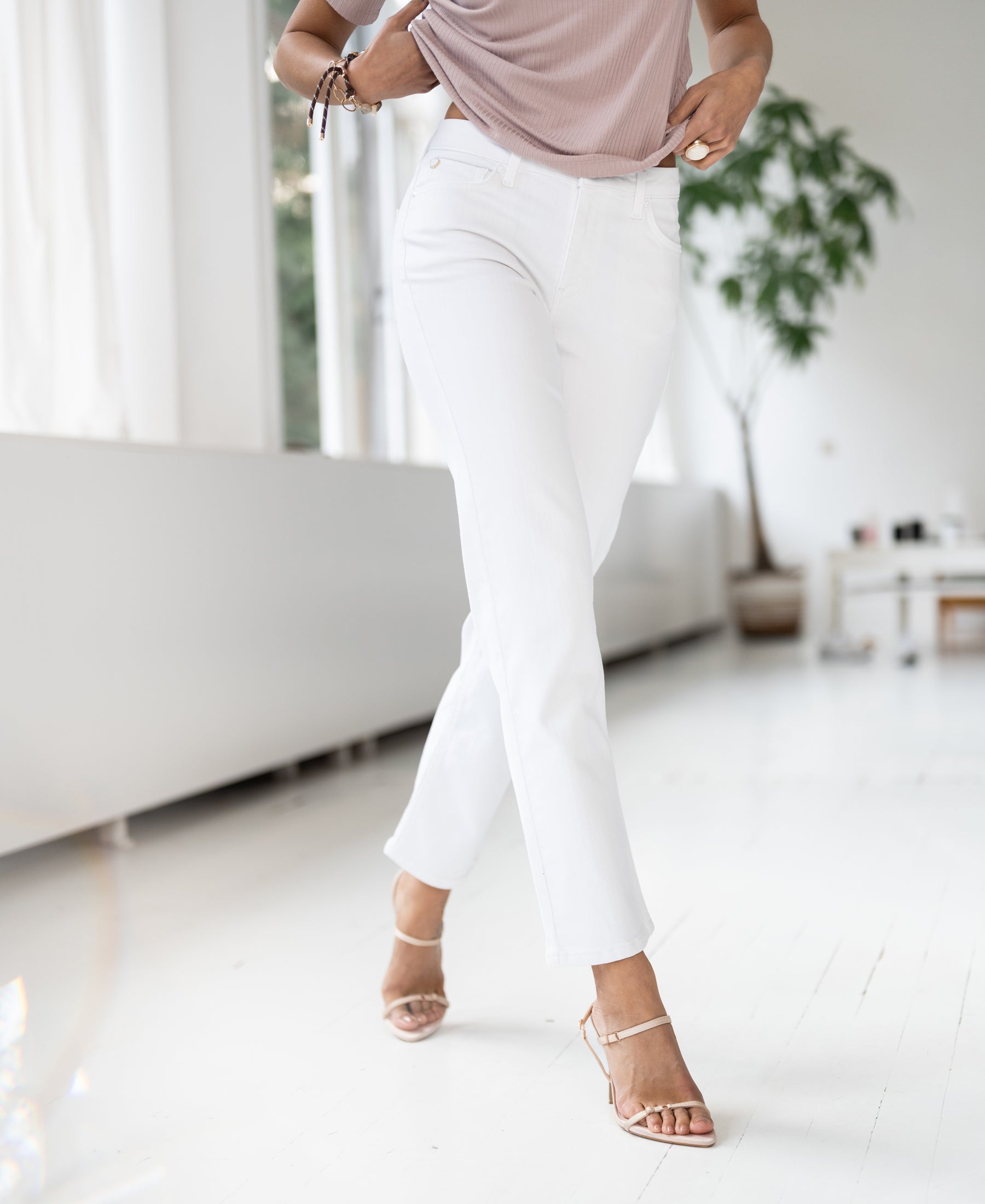 White straight-leg cropped jeans shown in a bright room with white floors.