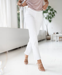 Cropped jeans with straight slim legs in white, shown in a modern, bright room.
