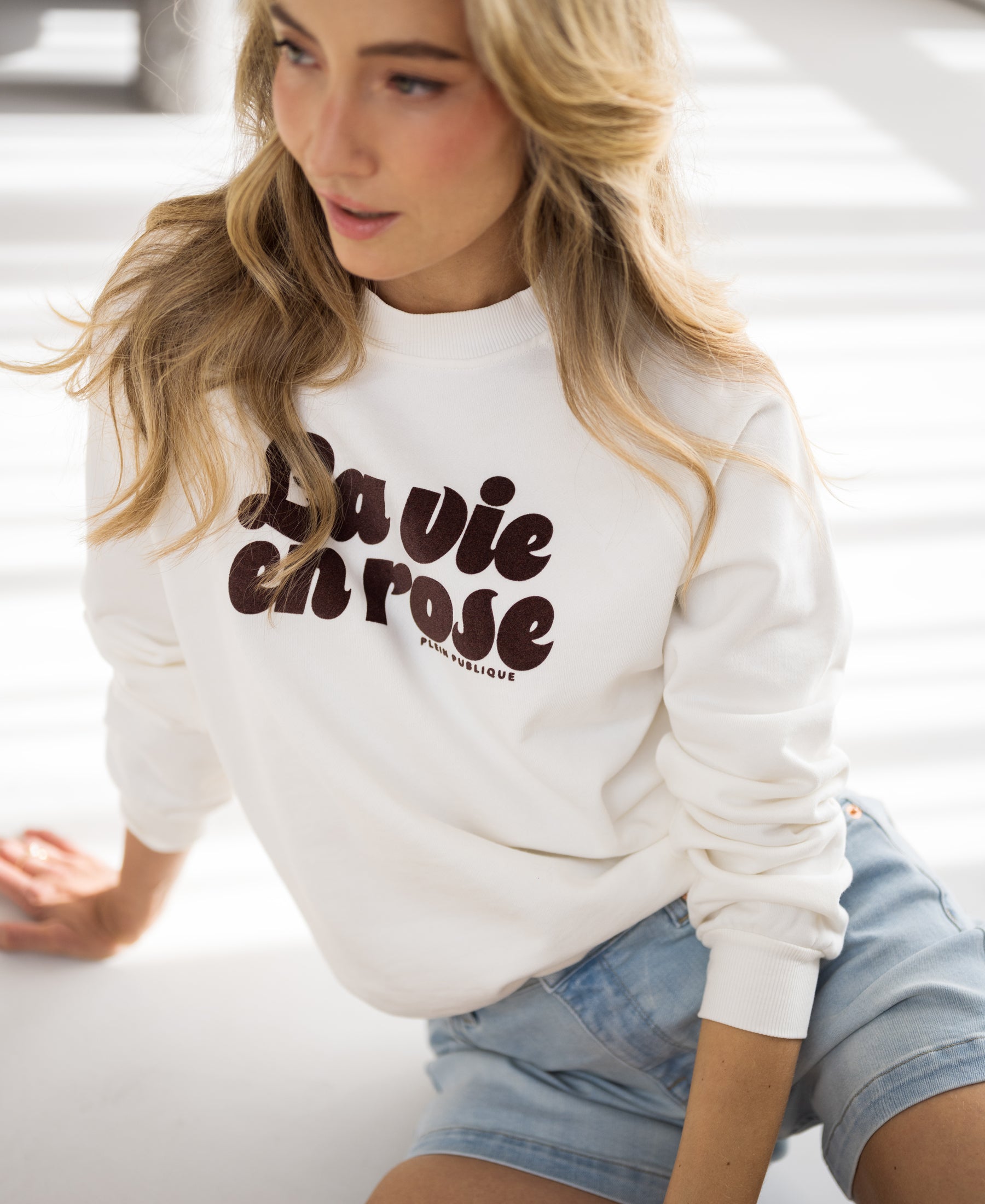 Ivory and cocoa LA HARPER sweater by PLEIN PUBLIQUE worn by a woman with long blonde hair.