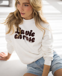 Ivory and cocoa LA HARPER sweater by PLEIN PUBLIQUE worn by a woman with long blonde hair.