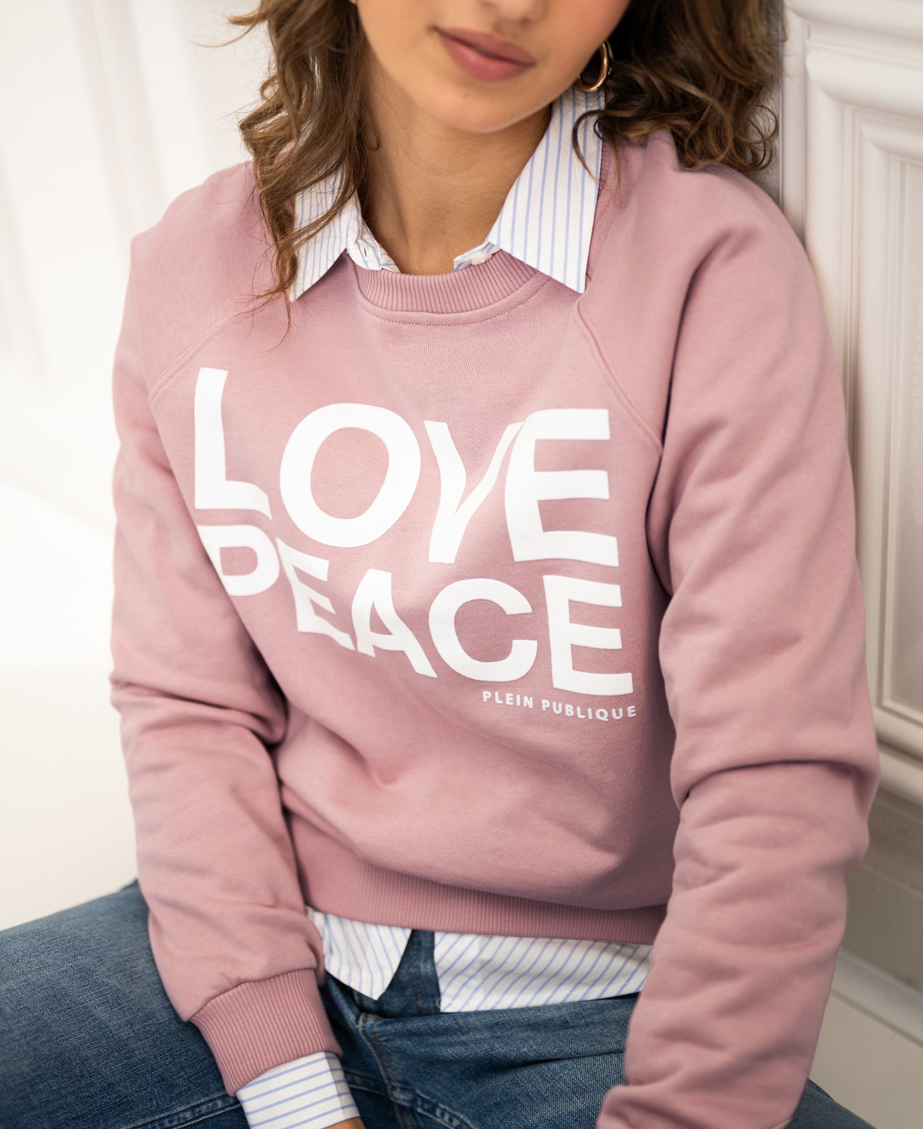 Woman wears an antique rose LOVE PEACE sweater from PLEIN PUBLIQUE, front view.