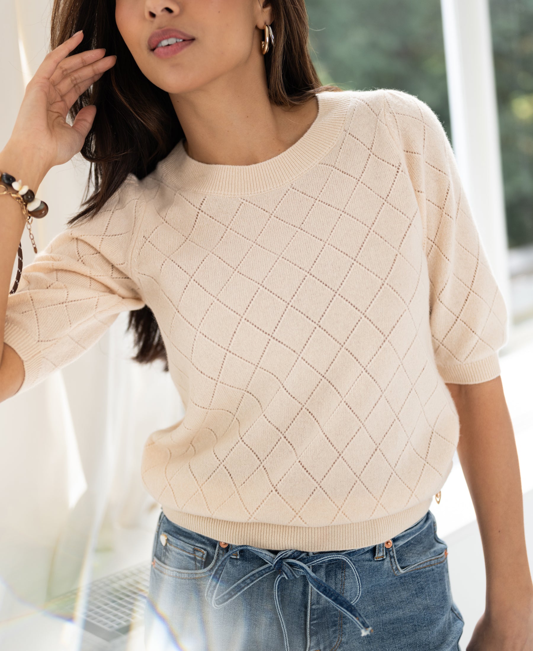 Woman wears the Argyle merino wool sweater in butter color.