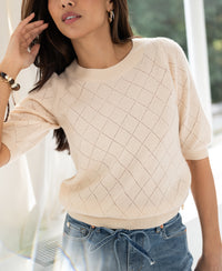 Woman wears the Argyle merino wool sweater in butter color.
