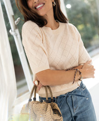 Woman wearing a butter yellow argyle merino wool sweater, LE HARVARD style.