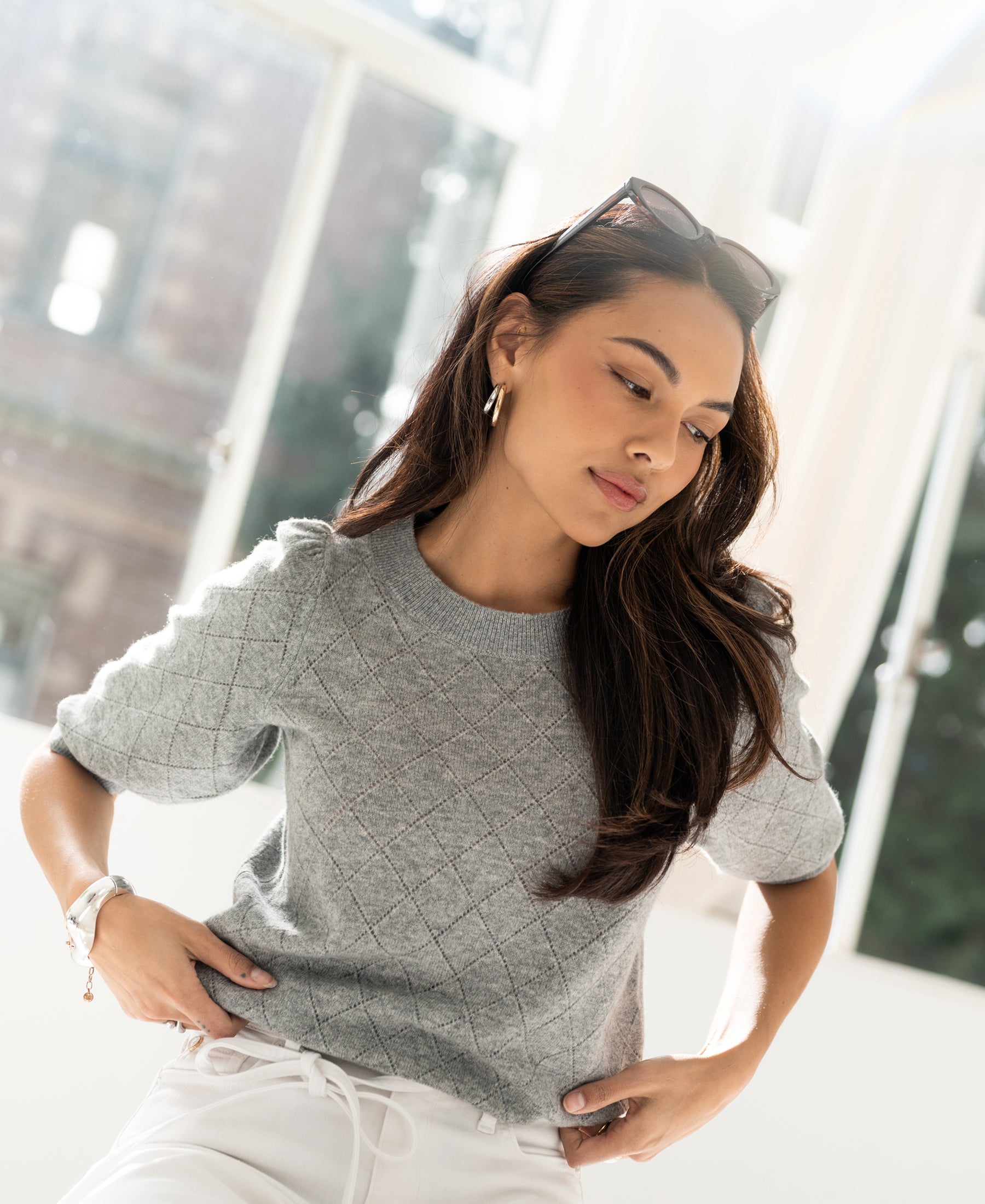 Grey argyle Merino wool sweater shown on a model by a bright window.