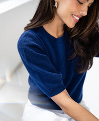 Navy argyle merino wool sweater with LE HARVARD design, shown in a bright, minimalist space.