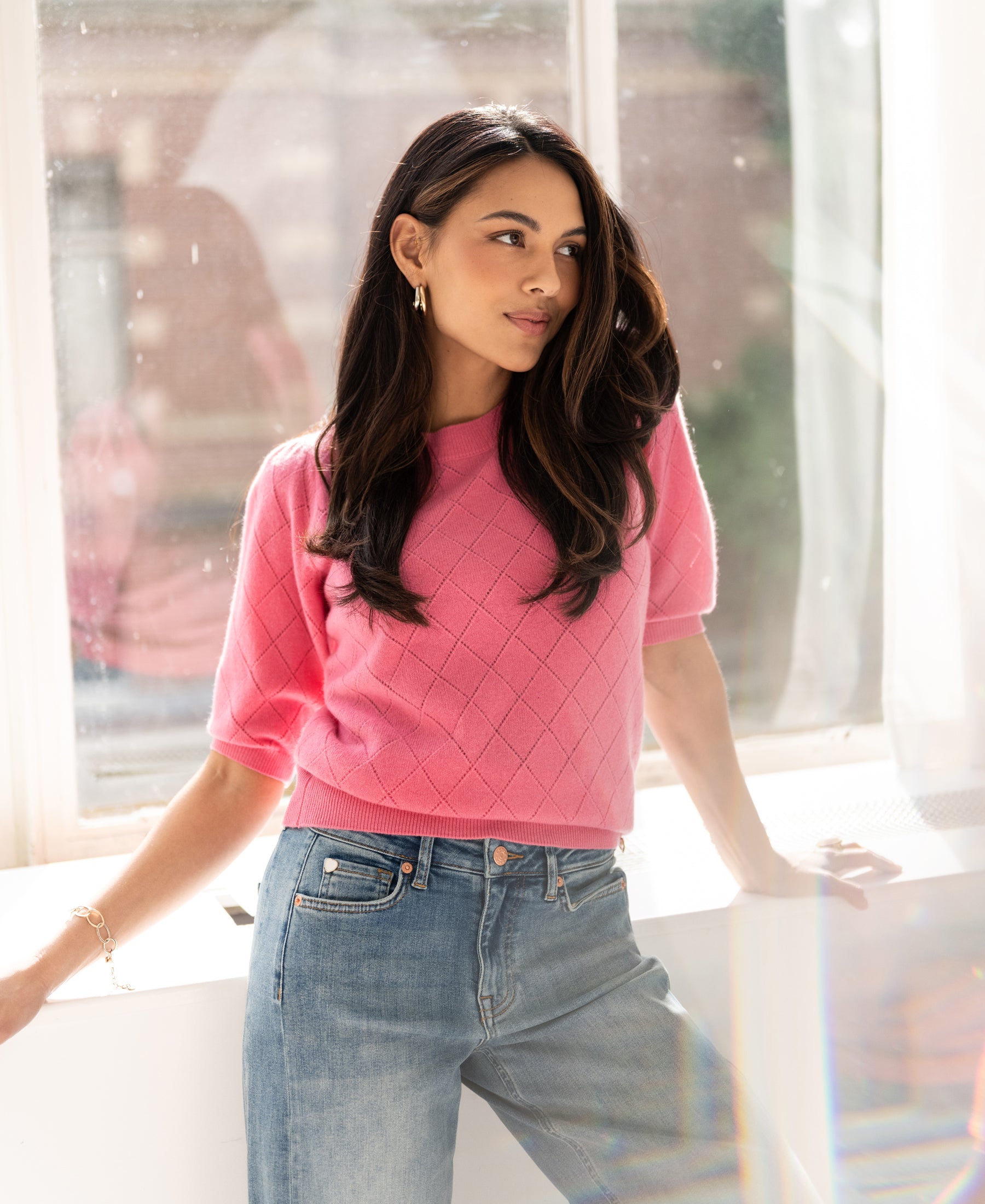 Light pink argyle merino sweater LE HARVARD by PLEIN PUBLIQUE displayed on a woman, side view.