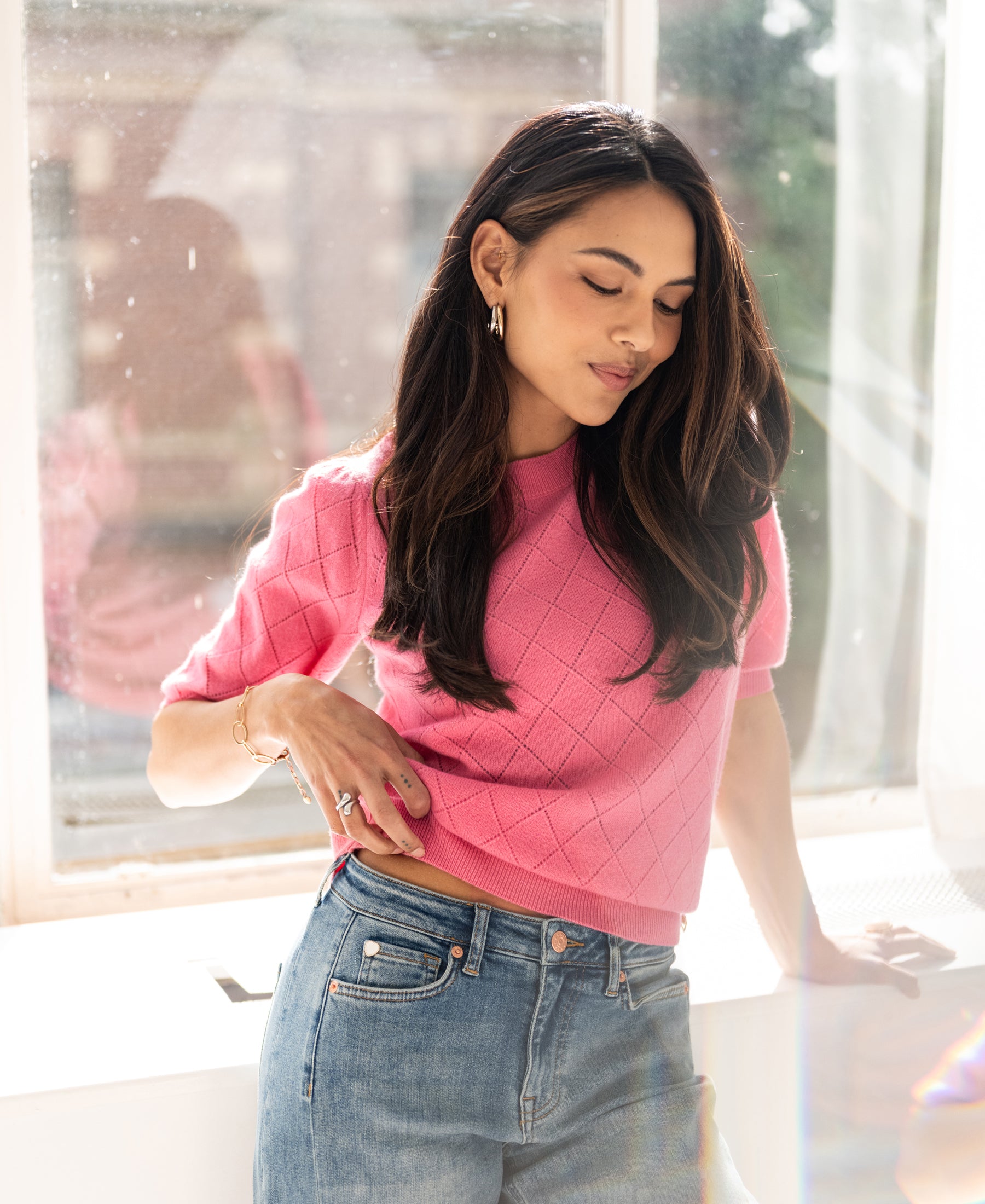 Pink argyle merino wool sweater featured in sunlight.