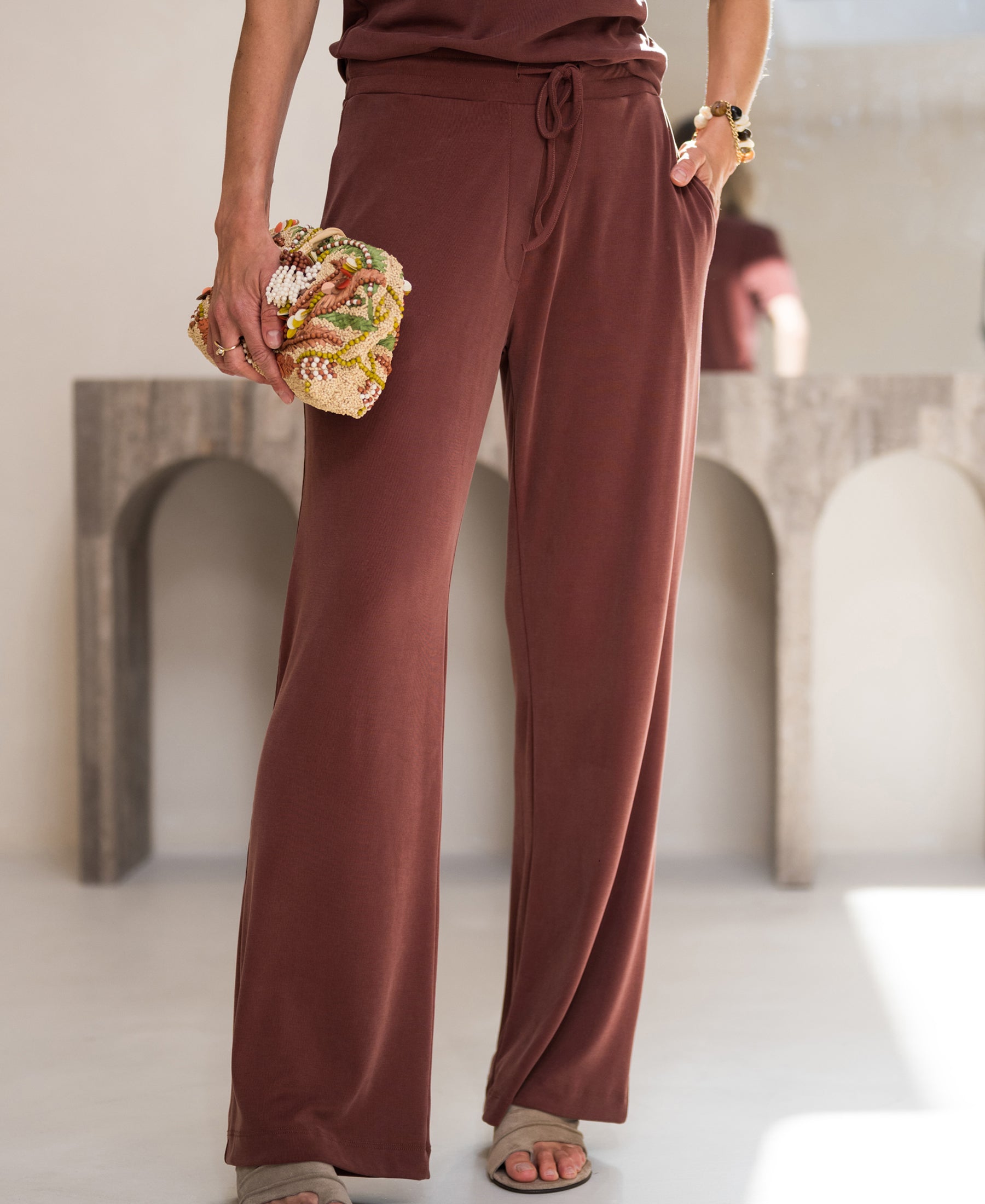 Relaxed fit lounge pants in henna color displayed on a light floor.