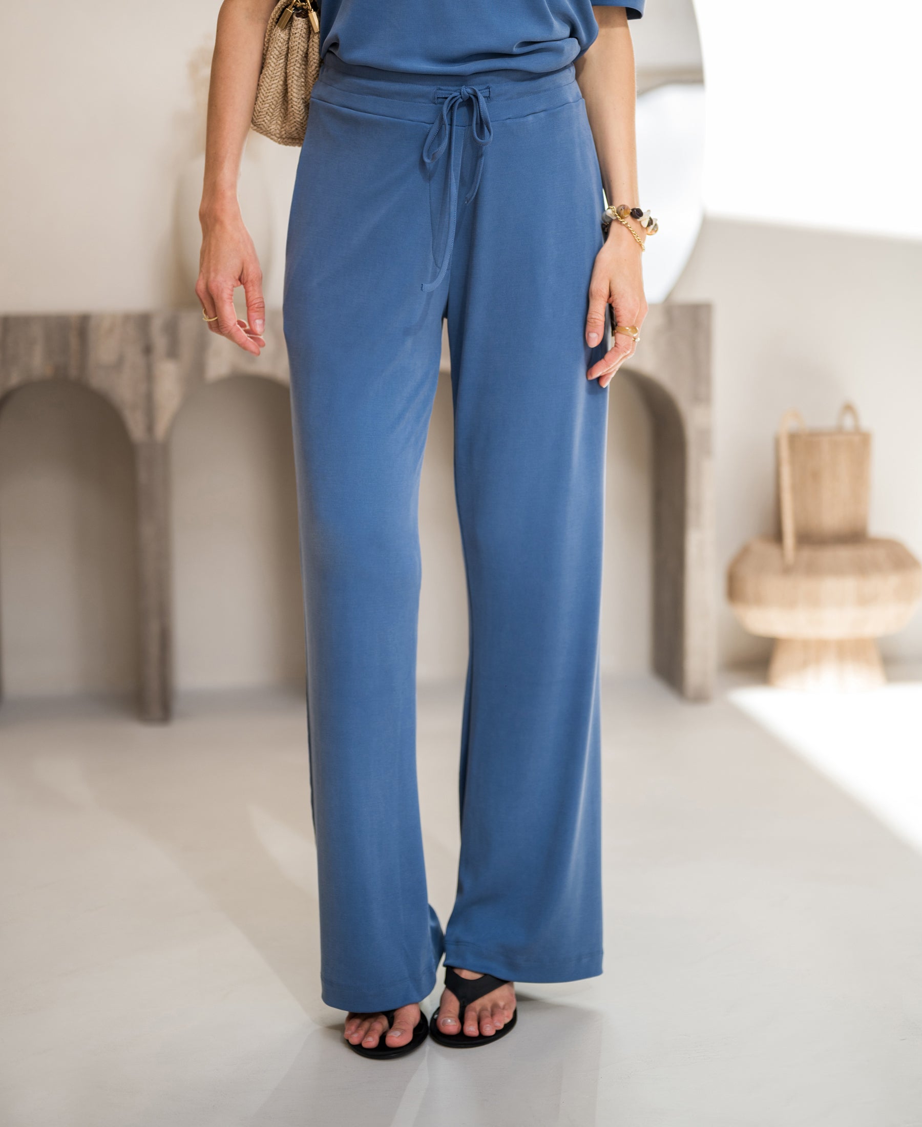 Person wearing blue lounge pants, standing indoors with neutral decor.