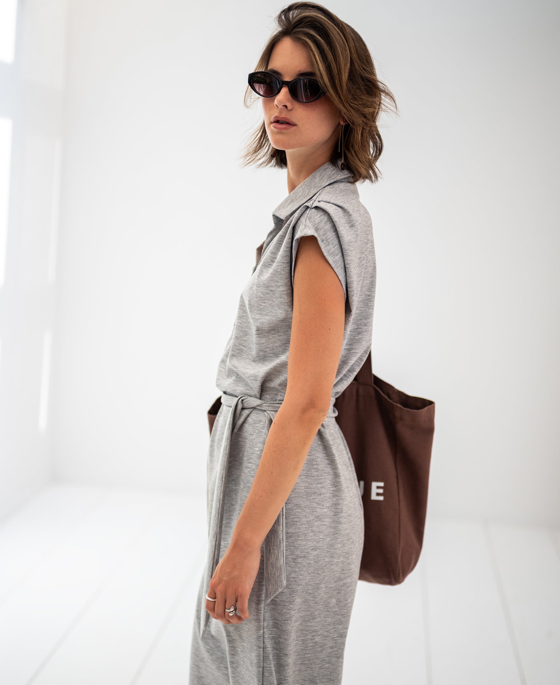 Woman wearing a grey mélange travel polo dress in a bright, minimalist room.