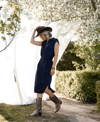 Woman wears the PLEIN PUBLIQUE Travel polo dress INES in dark blue outdoors near flowers.