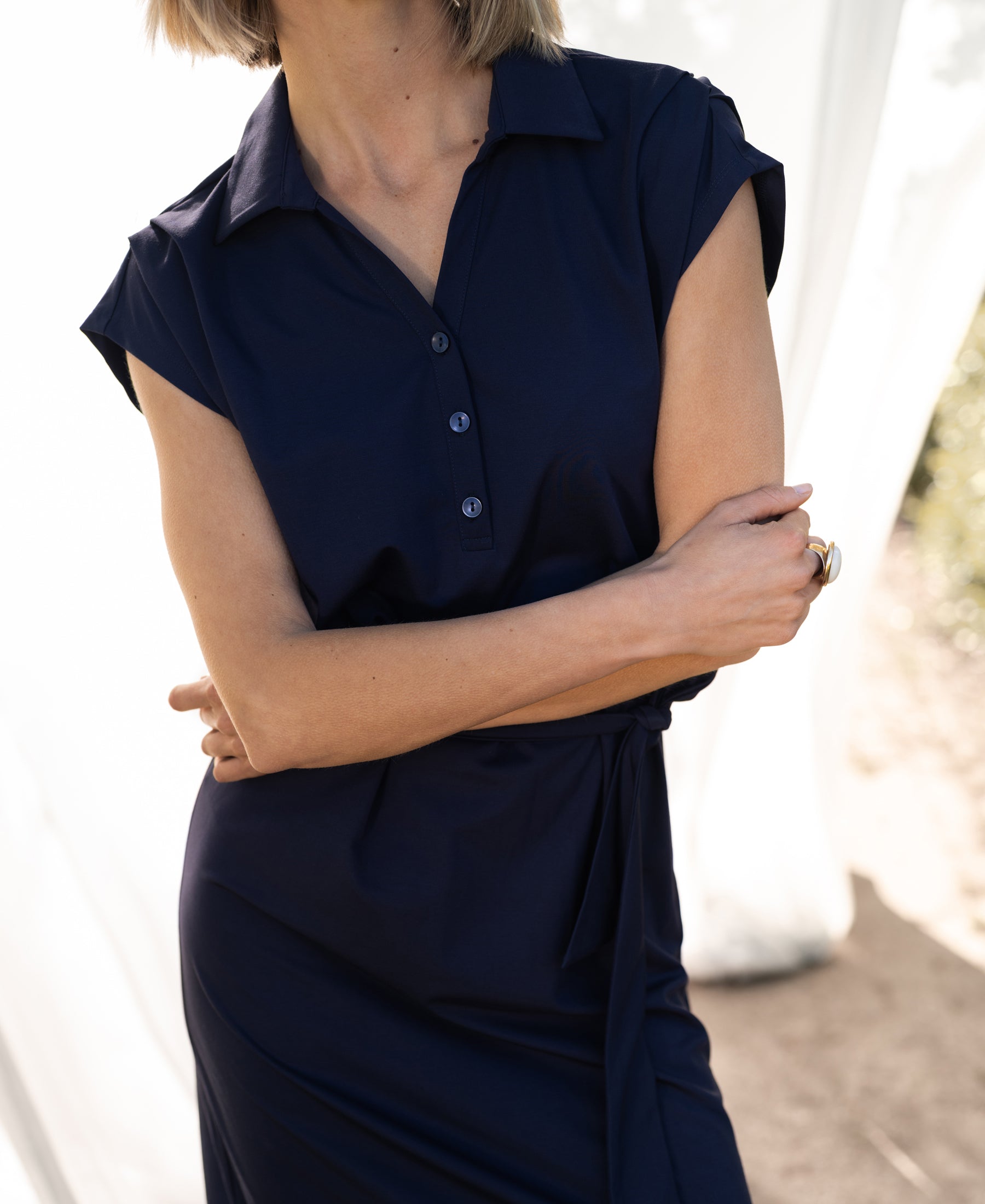 Navy PLEIN PUBLIQUE INES travel polo dress shown outdoors in soft sunlight.