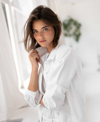 White denim jacket by Plein Publique, shown in a bright room with a plant.