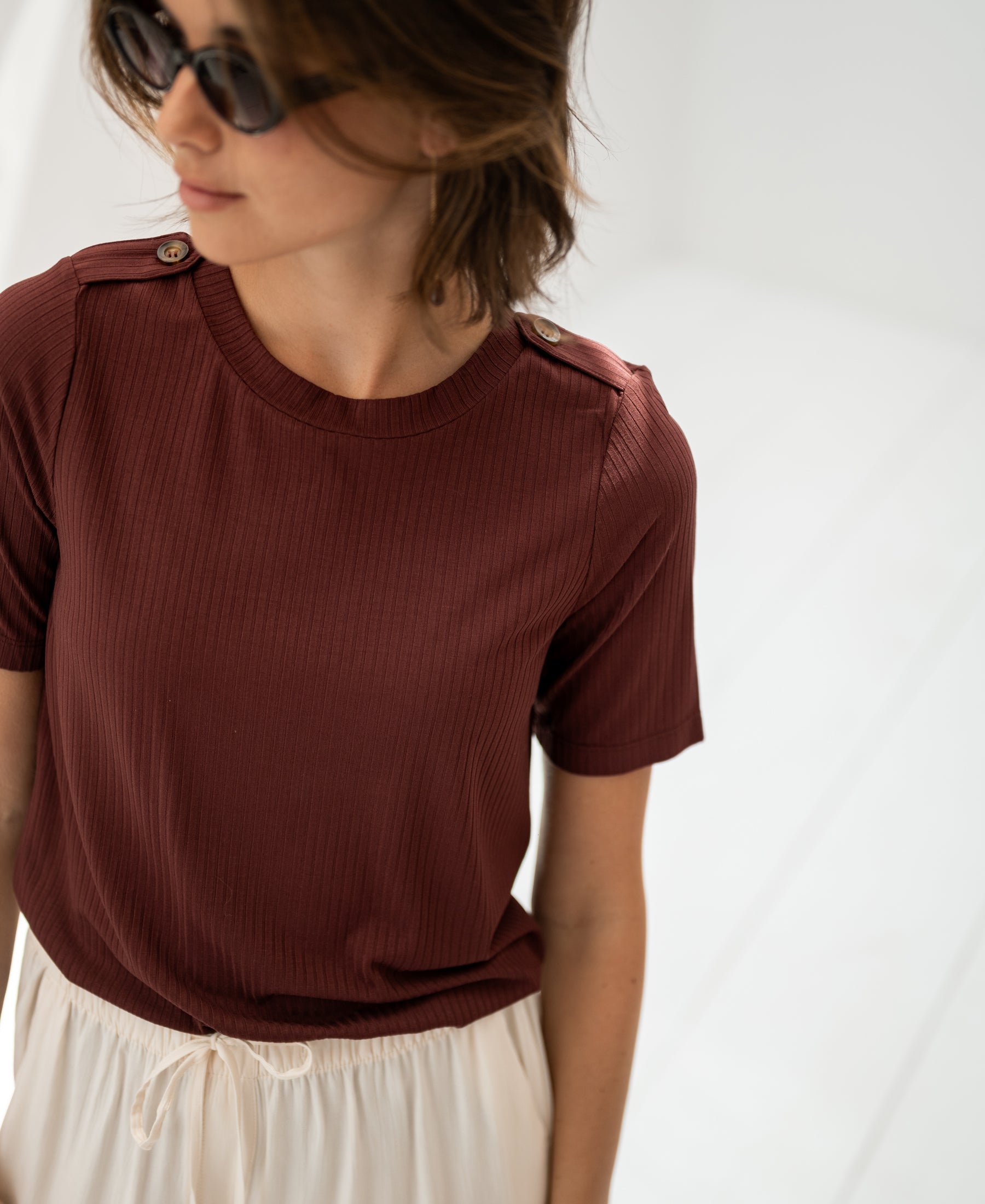 Woman wearing bamboo T-shirt in red-brown from PLEIN PUBLIQUE in a bright room.