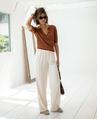 Woman wears the pleated public Tencel-silk polo shirt in Havana brown.