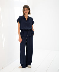 Navy blue LA JODY blouse by PLEIN PUBLIQUE shown on a woman in a minimalist white room.