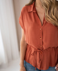 Terra-colored LA JODY blouse with waist tie by PLEIN PUBLIQUE, shown indoors.