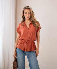 Woman wearing a terra-colored PLEIN PUBLIQUE LA JODY blouse indoors.