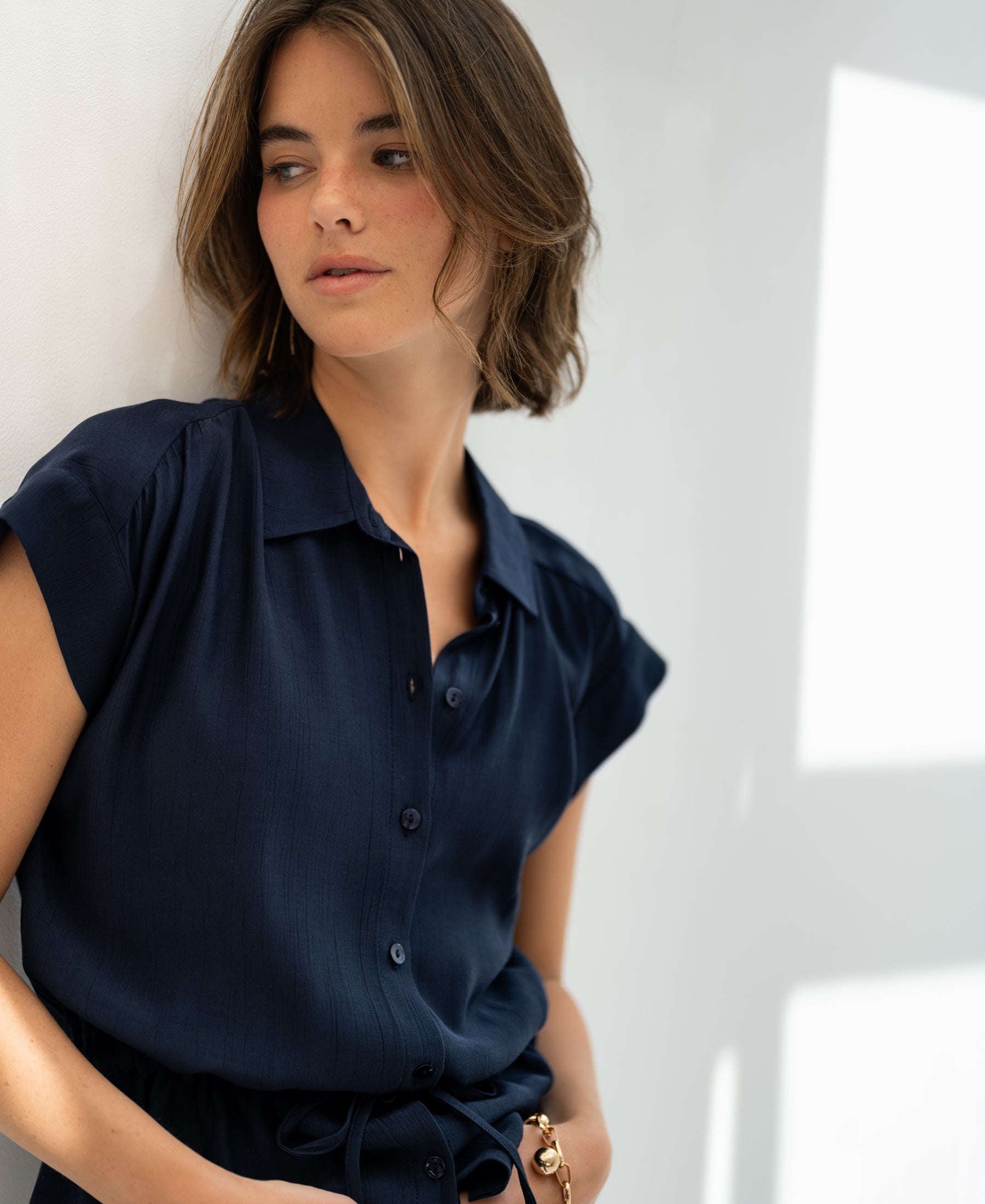 Dark blue PLEIN PUBLIQUE LA JODY blouse shown on model with short brown hair, side view.