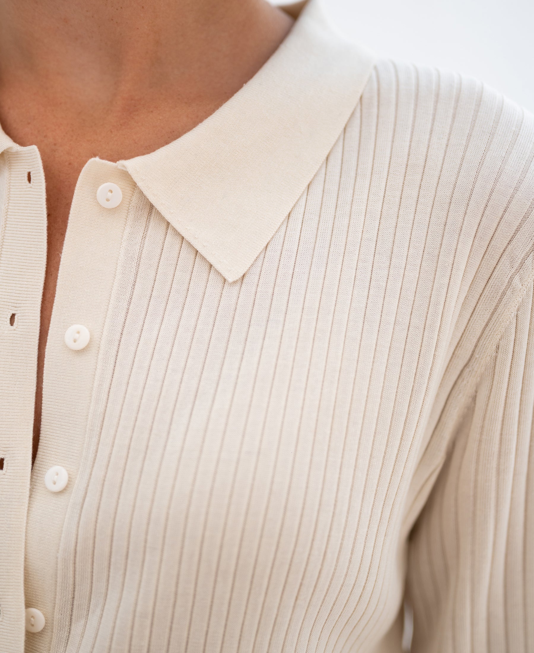 Close-up of a cream Tencel-silk ribbed vest with ribbed texture and classic collar.