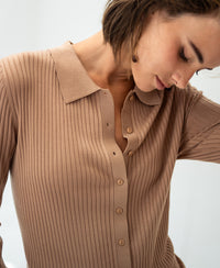 Tencel-silk ribbed cardigan in warm sand, front view. Model looks down with hair partly covering her face.