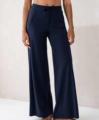 Navy blue travel pants with stretch waistband and side pockets, shown indoors.