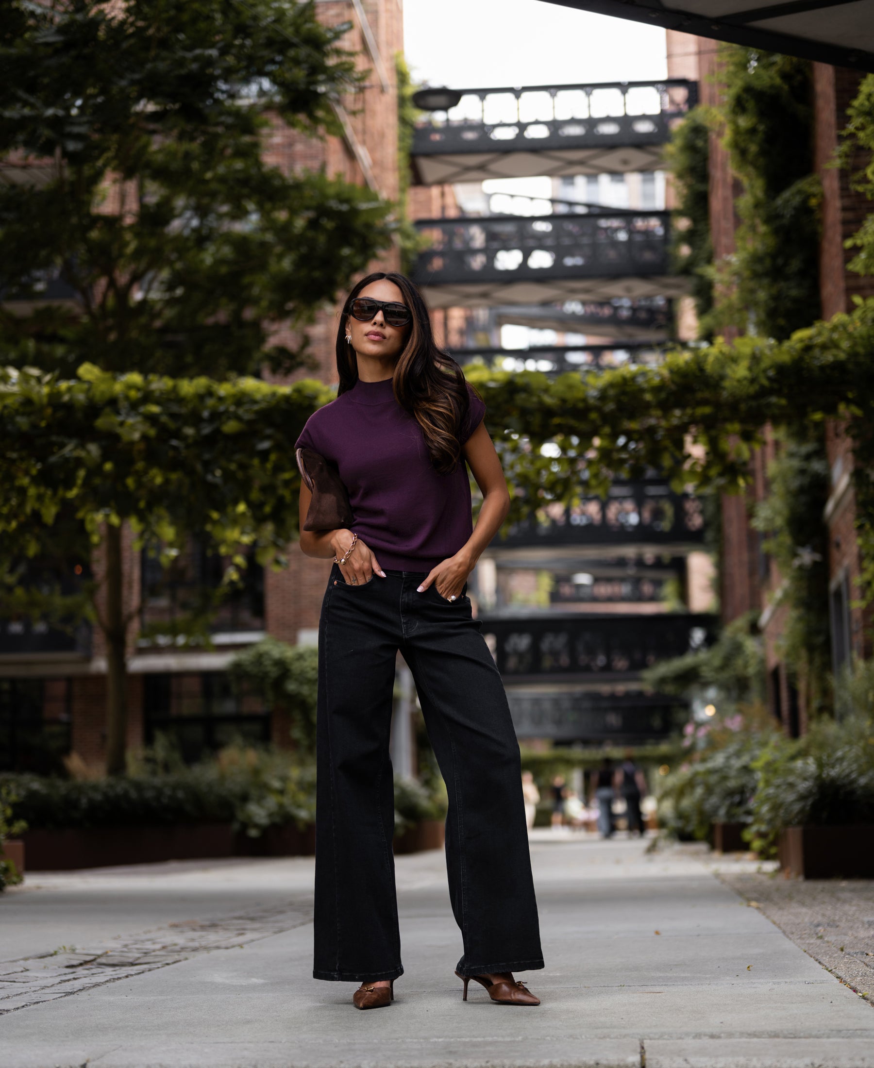 Woman wearing plum Merino wool collared top, seen outdoors on a city walkway.