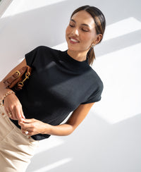 Woman wears black Merino wool top.
