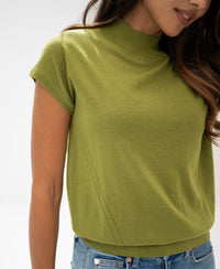 Woman wearing Merino wool top LE JULIAN in olive green against a plain light background.