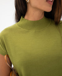 Woman wears olive green merino wool top, photographed from the shoulders up.