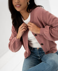 Woman wearing a dusty pink round neck vest, adjusting the buttons.