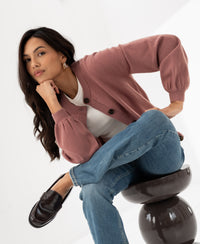 Dusty pink round neck cardigan by PLEIN PUBLIQUE called LA LEA, shown on a seated woman.
