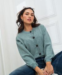 Woman wears a PLEIN PUBLIQUE round neck vest in light green, seated indoors.