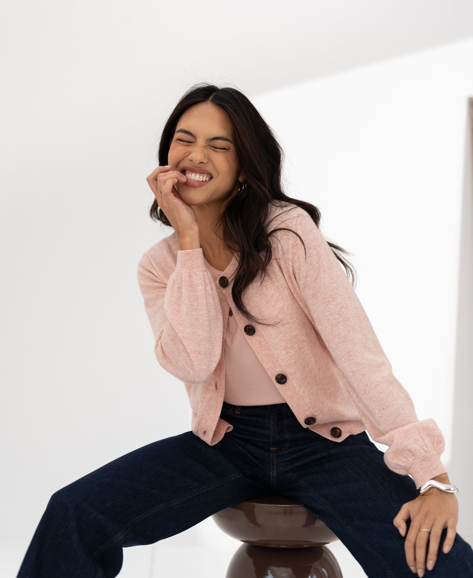 Woman wearing a pink LA LEA round neck vest by PLEIN PUBLIQUE, smiling with eyes closed, hand on her face.