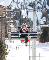 Breton sweater L'ELISA in ivory-black by PLEIN PUBLIQUE shown, with snowy peaks and buildings in the background.