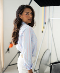 Striped blouse in light blue and coral is shown in a bright studio.