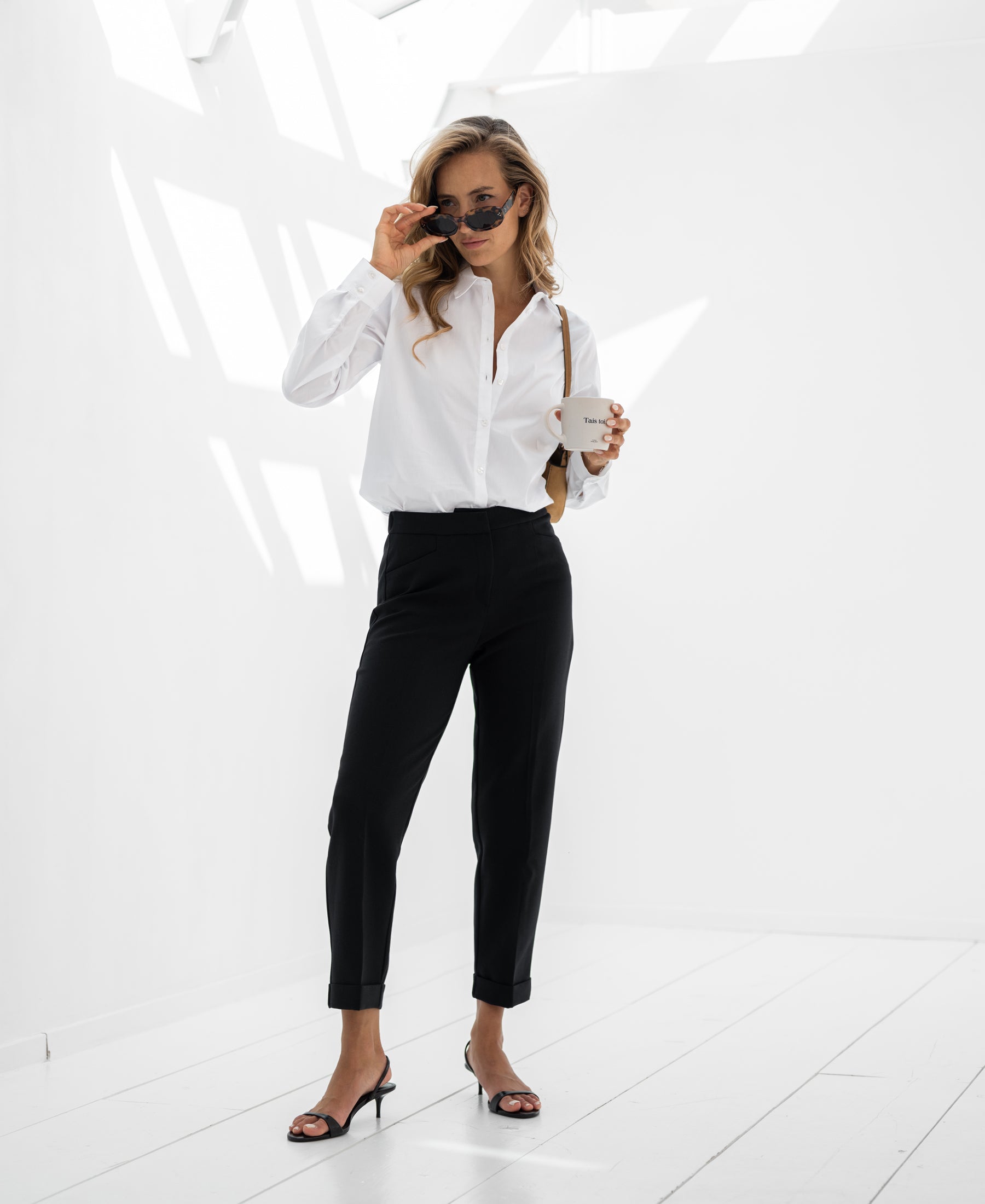 Woman wearing black PLEIN PUBLIQUE 7/8 LE FAUBOURG pants, standing in a bright room.