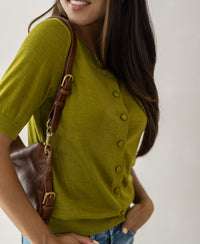 Woman wearing a Merino wool silk cardigan LA LORAINE by PLEIN PUBLIQUE, smiling against a light background.