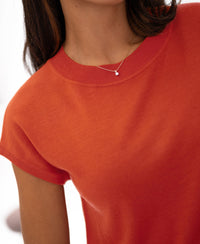 Person wearing a chili red Merino wool top, shown from shoulders to chin.