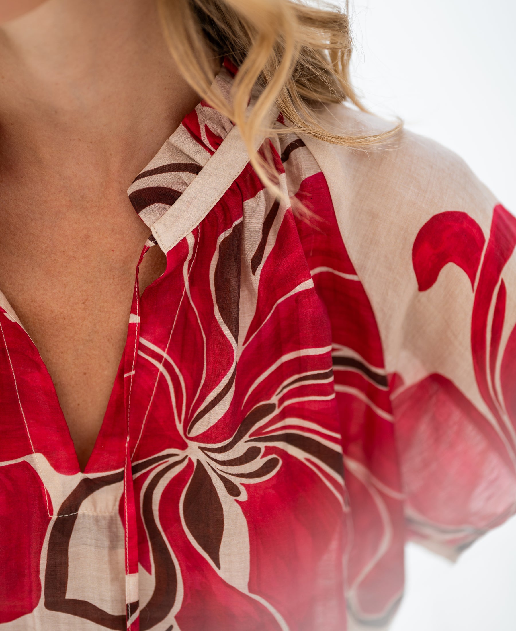 Ruby Red LA LUNETTE blouse top with bold floral print and butterfly sleeves, shown neck to upper chest.