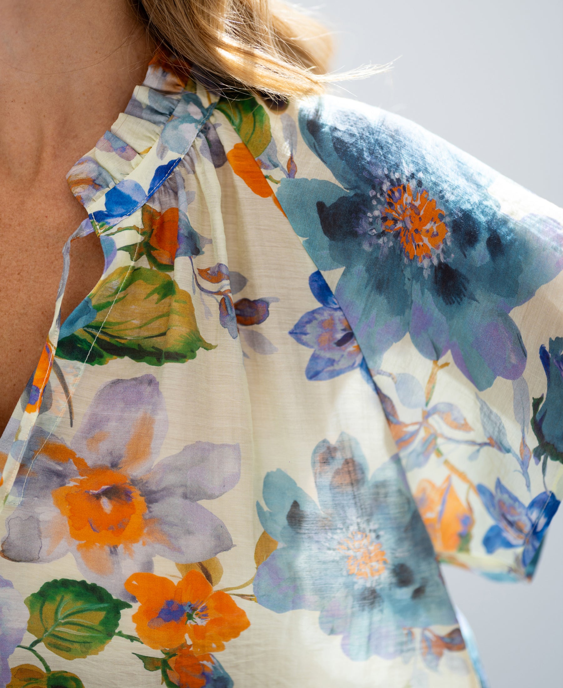 A close-up of a light blue floral print blouse top with butterfly sleeves from PLEIN PUBLIQUE.
