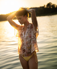 Woman (173cm, size S) wears a PLEIN PUBLIQUE blush floral print blouse top by the lake at sunset.