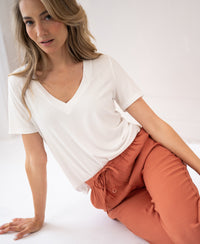 Woman seated on the floor wearing terra-colored LA LYNETTE trousers from PLEIN PUBLIQUE.