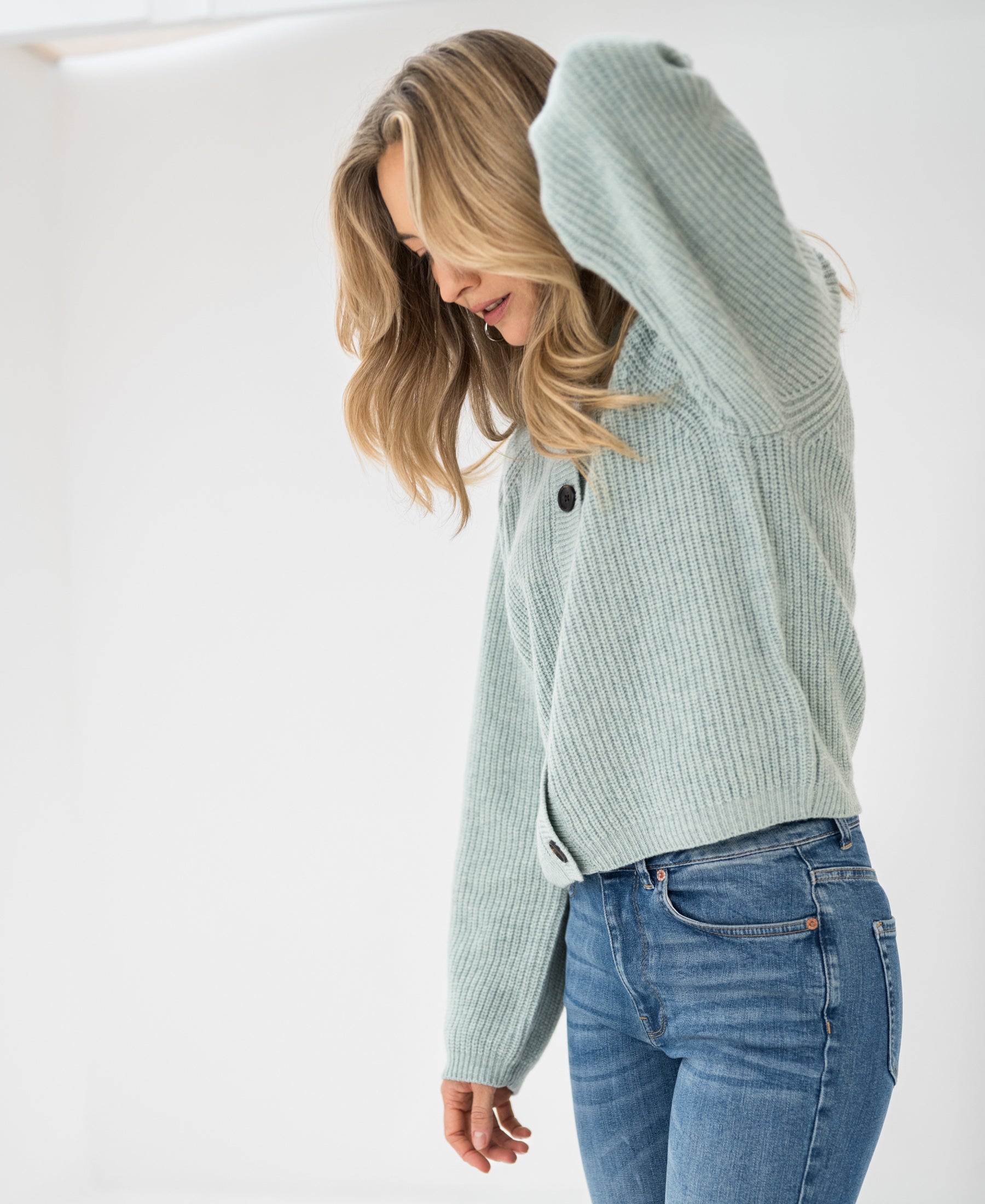 Mist green merino wool vest shown against white background. Model facing down, one arm raised.