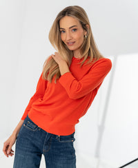 Coral red PLEIN PUBLIQUE LA MARCEAU merino wool sweater shown on model in a bright room.