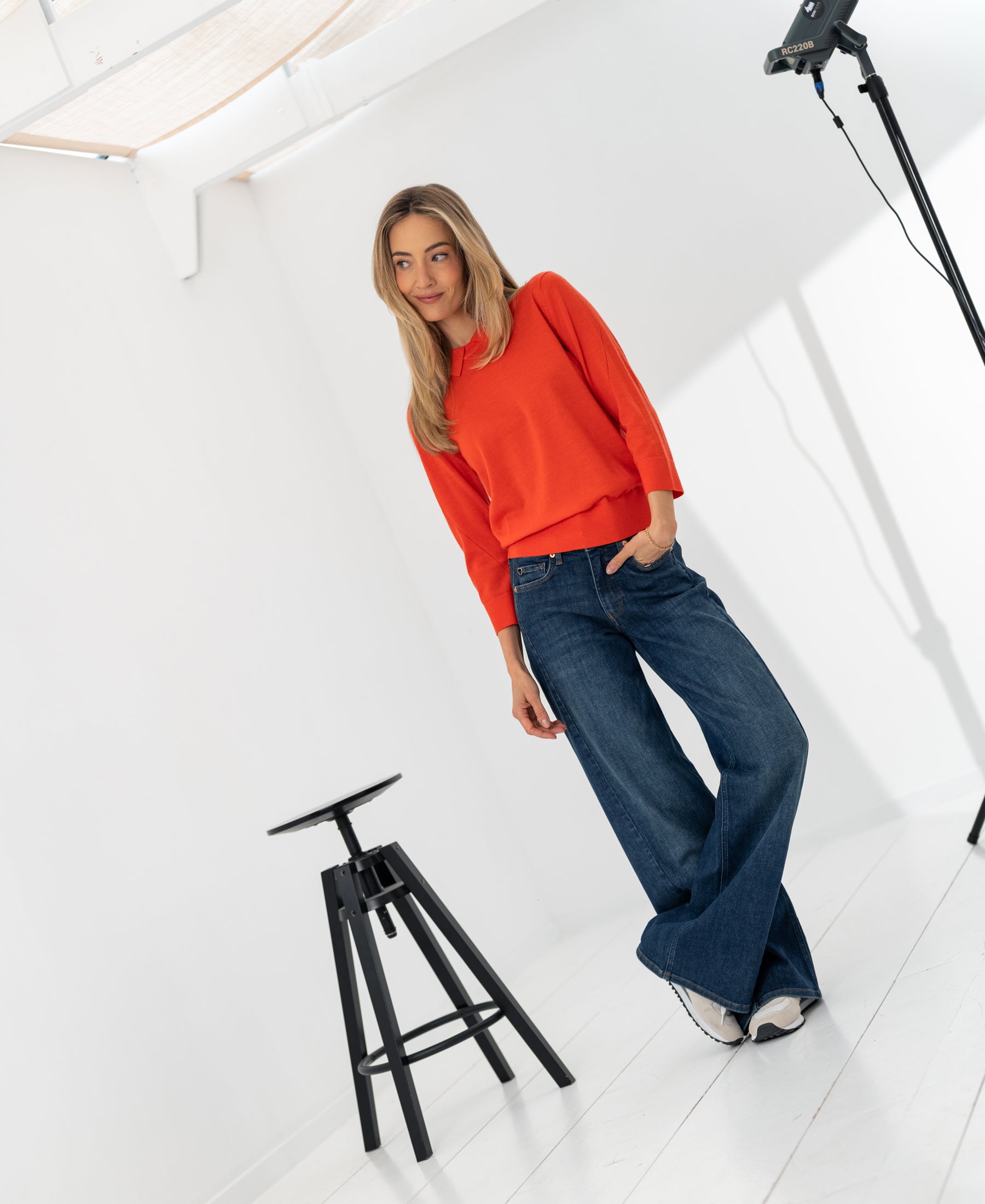 Woman wearing coral red PLEIN PUBLIQUE Merino wool polo-collar sweater LA MARCEAU in studio.