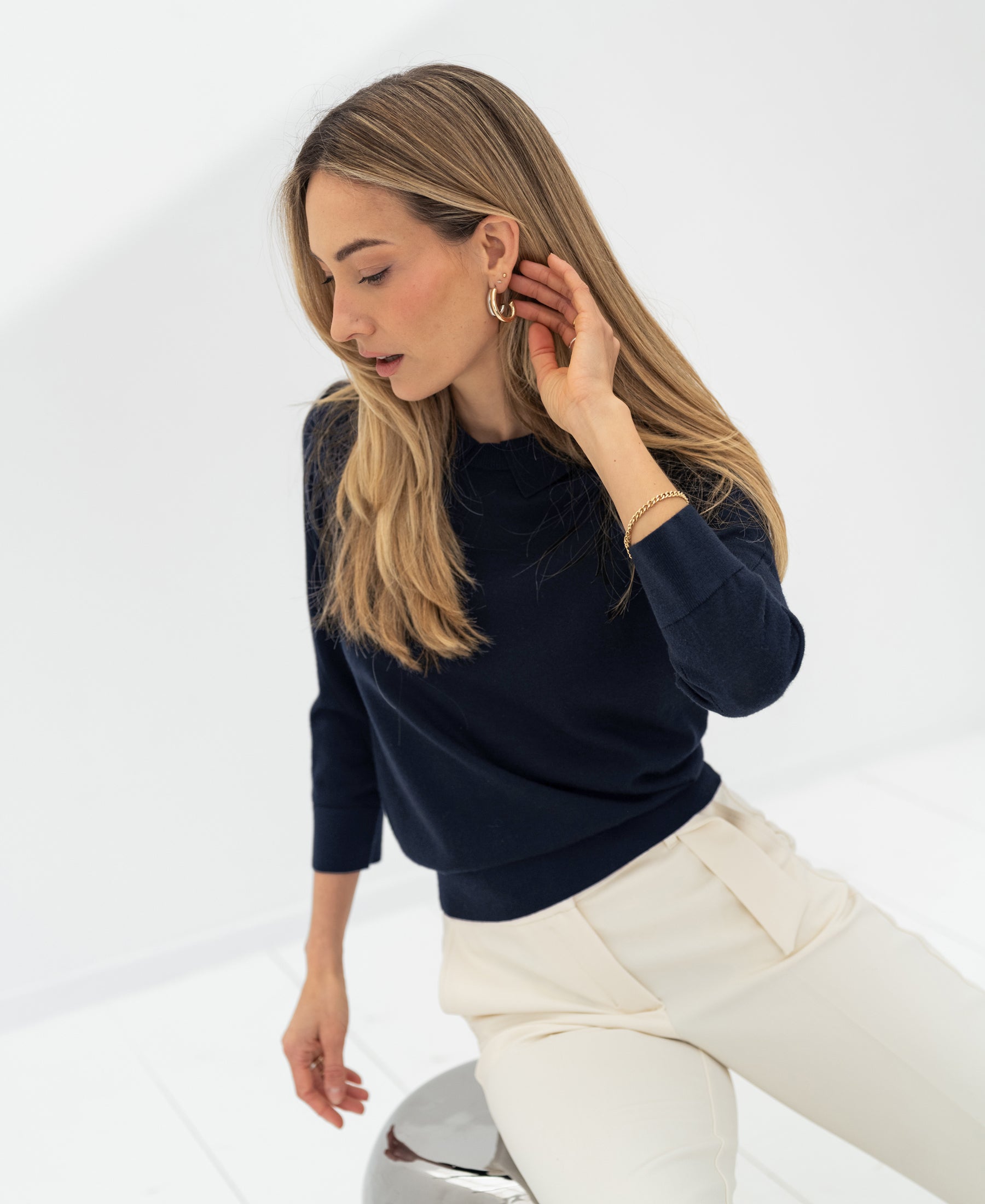 Woman wearing a dark blue merino wool polo collar sweater.