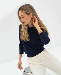 Woman wearing a dark blue merino wool polo collar sweater.