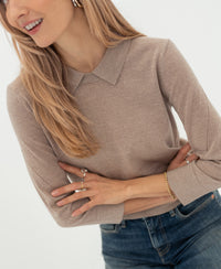 Merino wool polo collar jumper LA MARCEAU Sand by PLEIN PUBLIQUE, shown by a blonde woman with crossed arms, smiling.